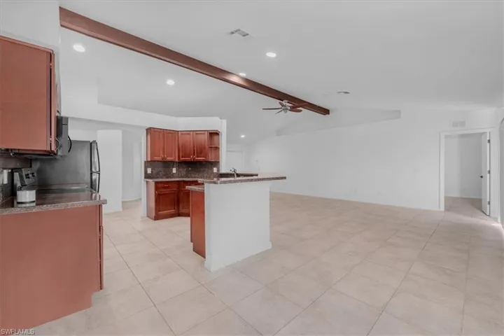 Kitchen with ceiling fan, open shelves, light tile patterned floors, vaulted ceiling with beams, and recessed lighting