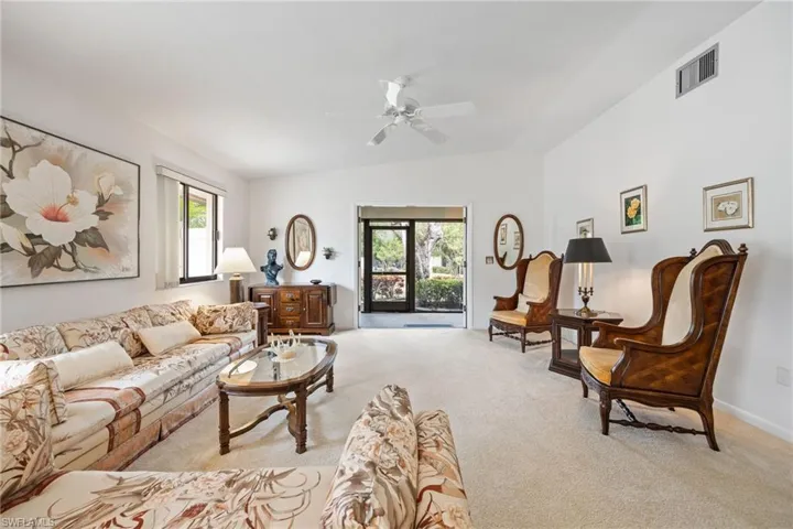 Carpeted living room with lofted ceiling and a ceiling fan