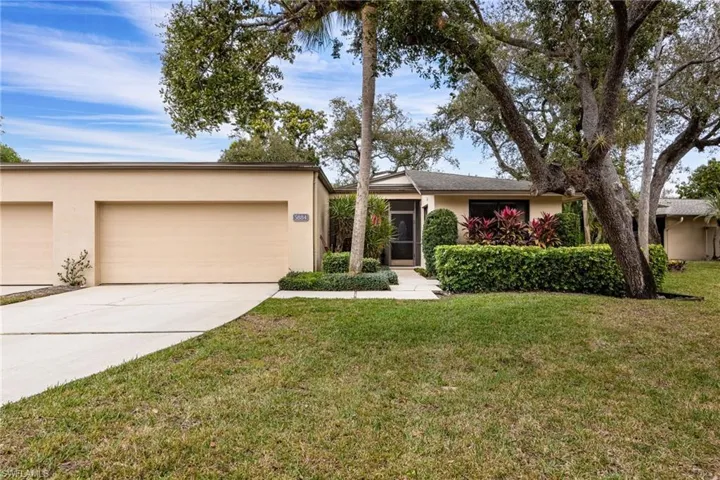 View of front facade with stucco siding, a front lawn, driveway, and an attached garage