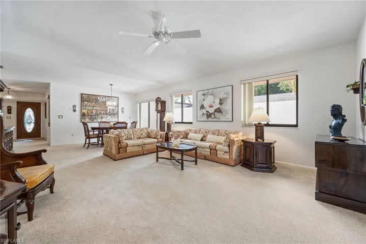 Living room with light colored carpet, lofted ceiling, and ceiling fan