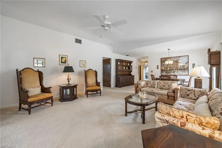 Living room featuring a chandelier, light carpet, and ceiling fan