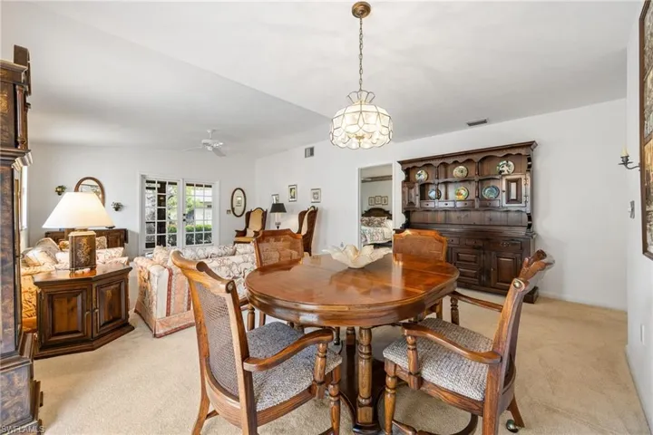 Dining area with light colored carpet, a chandelier, vaulted ceiling, and ceiling fan