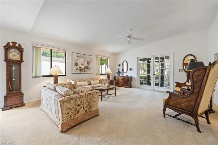 Living area featuring vaulted ceiling, light carpet, and ceiling fan