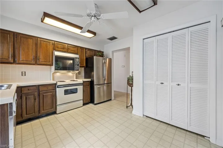 Kitchen featuring light countertops, stainless steel appliances, decorative backsplash, light floors, and ceiling fan