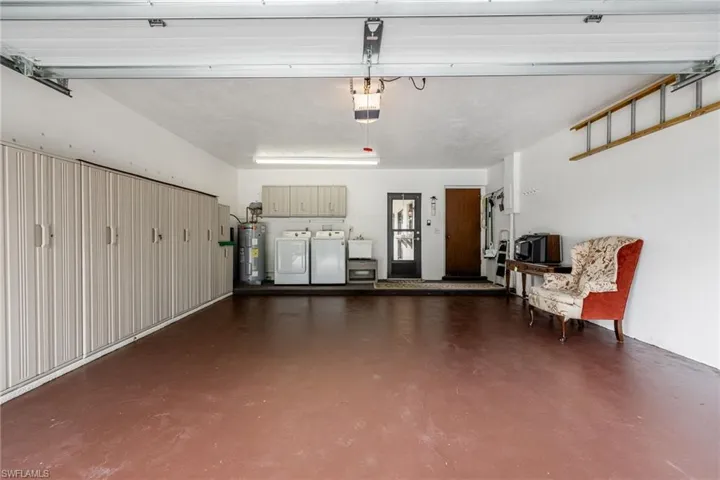 Garage featuring washer and clothes dryer, electric water heater, and a garage door opener