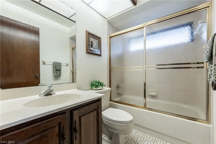 Full bath featuring vanity, shower / bath combination with glass door, and tile patterned floors