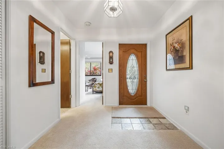 Foyer entrance featuring light colored carpet and baseboards