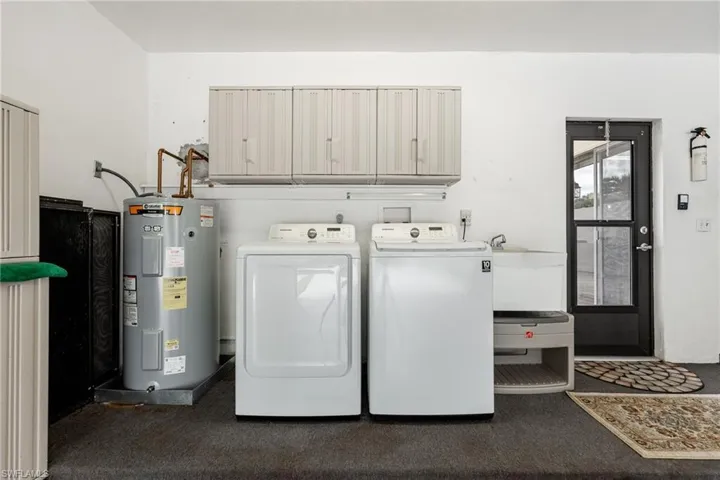 Laundry room featuring water heater, washer and clothes dryer, and cabinet space