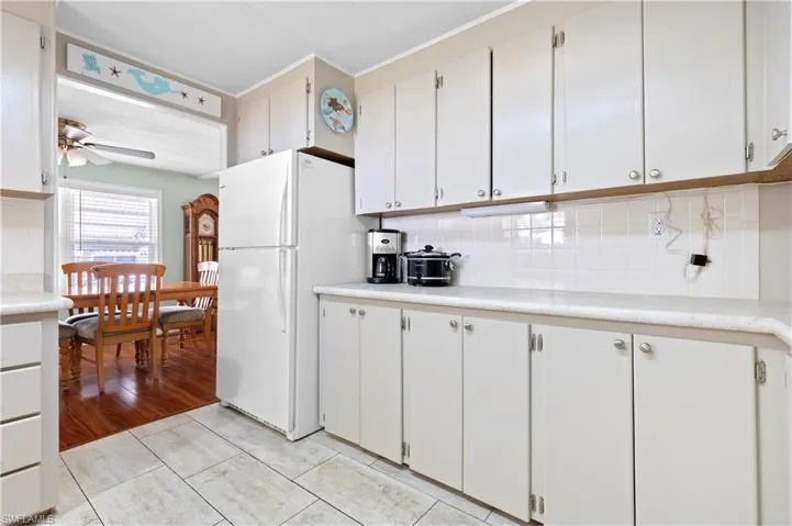 Kitchen with light countertops, crown molding, a ceiling fan, backsplash, and freestanding refrigerator