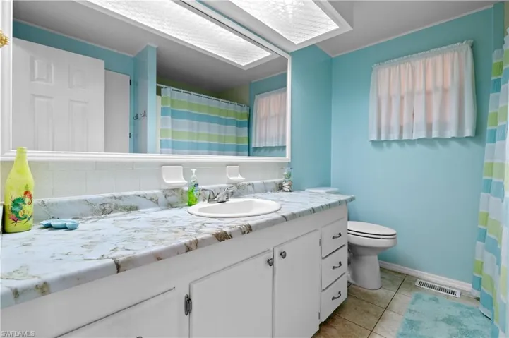 Primary bathroom featuring visible vents, baseboards, toilet, vanity, and tile patterned flooring