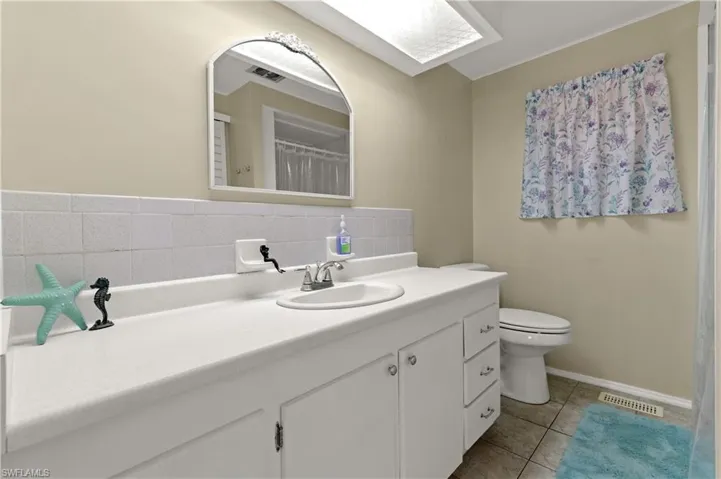 Full bath featuring visible vents, tile patterned flooring, toilet, vanity, and backsplash
