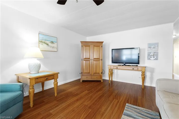 Living area featuring a ceiling fan, dark wood-type flooring, and baseboards