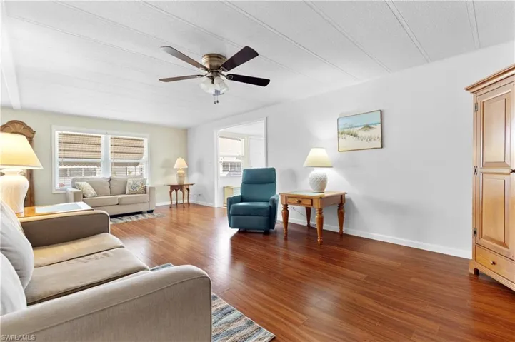 Living room with a ceiling fan, baseboards, and wood finished floors