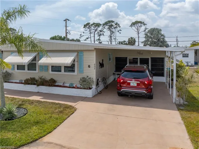 View of front facade with an attached carport and concrete driveway