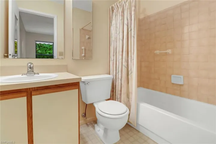 Full bathroom featuring shower / bath combo with shower curtain, vanity, tile patterned floors, and toilet