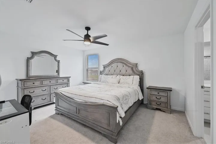 Bedroom with light carpet, ceiling fan, and connected bathroom