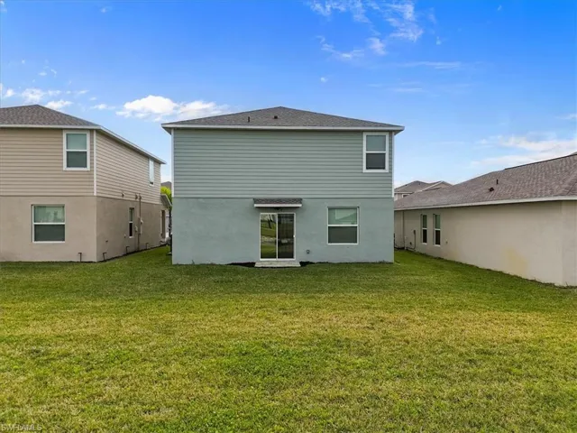 Rear view of house featuring a lawn and stucco siding