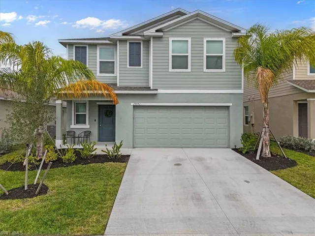 Traditional-style home with concrete driveway, stucco siding, a garage, and a front lawn