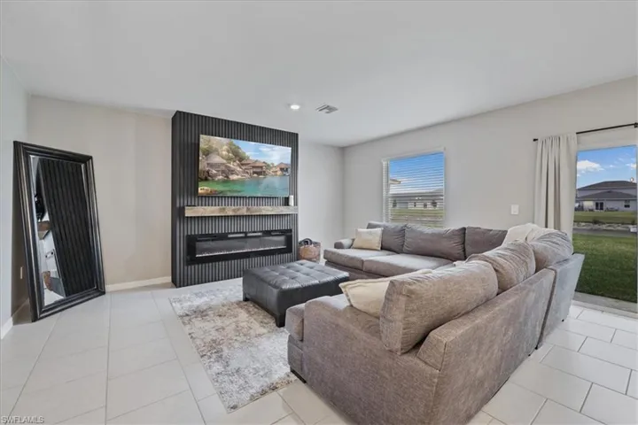 Living room featuring a glass covered fireplace, light tile patterned floors, and recessed lighting