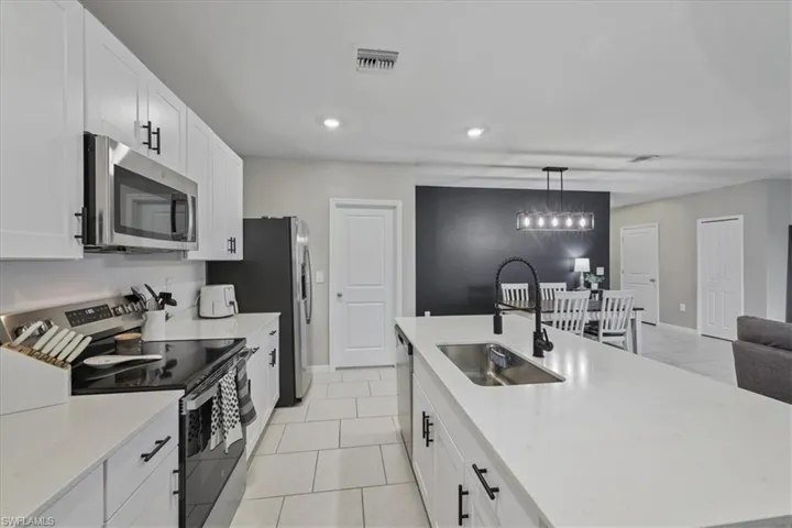 Kitchen with stainless steel appliances, white cabinets, pendant lighting, light tile patterned floors, and recessed lighting