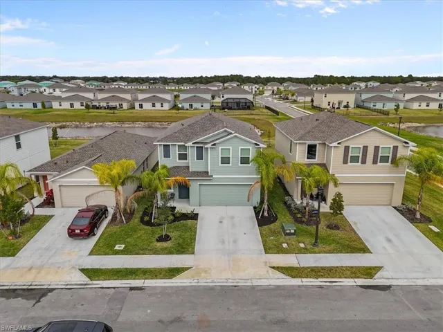 View of front facade with driveway, a garage, a residential view, a front yard, and stucco siding