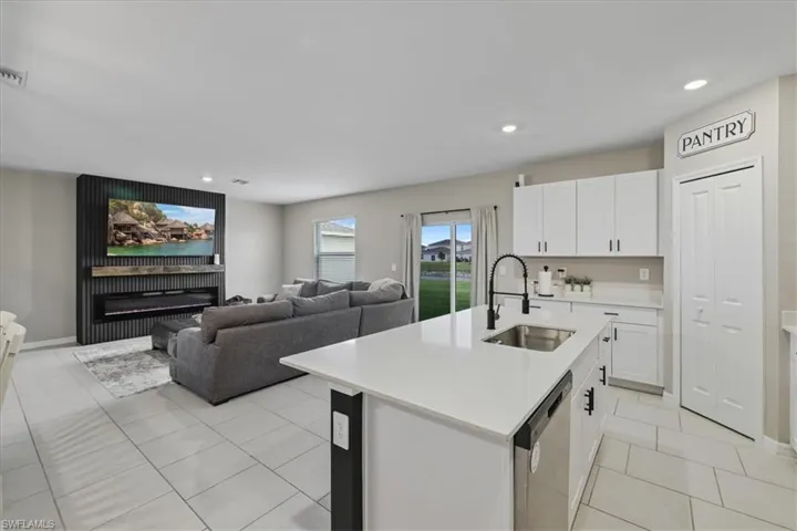 Kitchen featuring white cabinetry, stainless steel dishwasher, a center island with sink, recessed lighting, and open floor plan