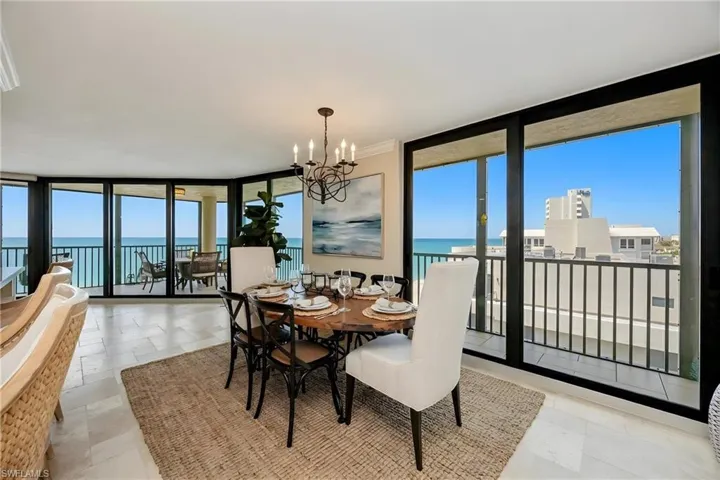 Dining area with expansive windows, a chandelier, a water view, and light stone finish floors