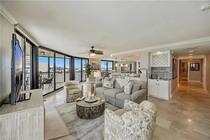 Living area with ornamental molding, a ceiling fan, and floor to ceiling windows