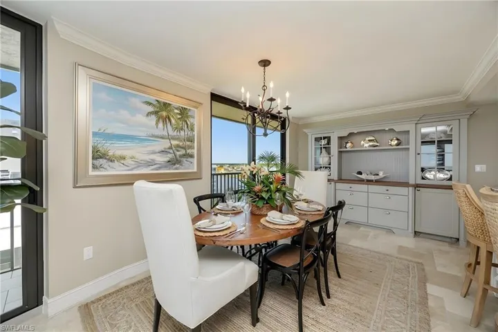 Dining area with suspended lighting, ornamental molding, and light stone finish floors