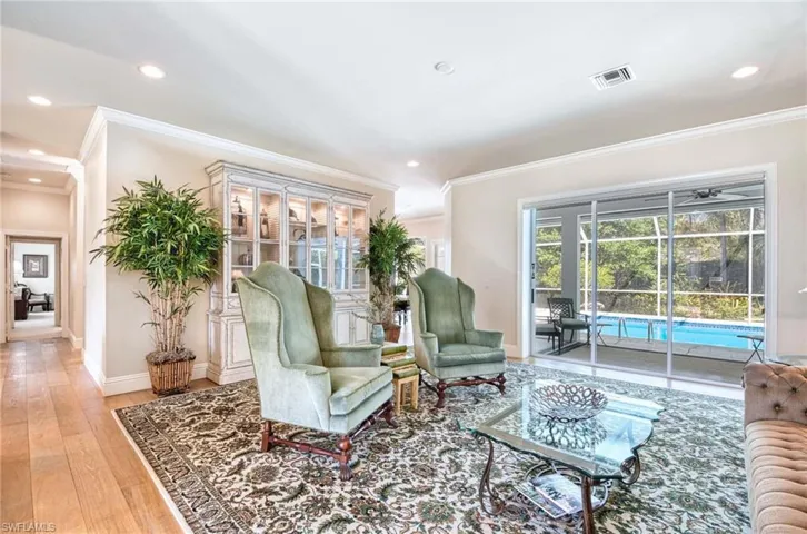 Living room with crown molding, hardwood flooring, recessed lighting, an oversized slider that leads to the lanai.
