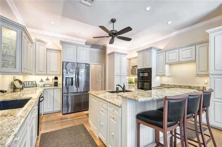 Chef's Kitchen with two sinks, stainless refrigerator with ice dispenser, ceiling fan, plus lots of cabinets.