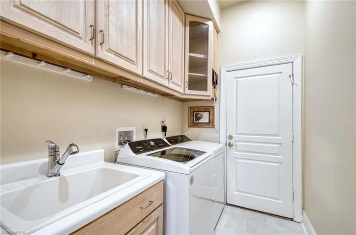Laundry area featuring upper cabinets, washer and dryer, and deep sink.
