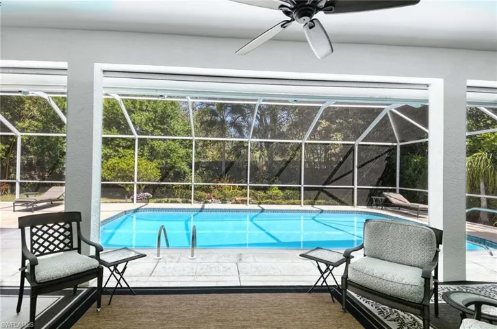 Outdoor pool with screened lanai, ceiling fan, and covered patio.