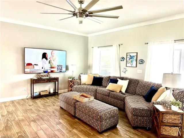 Living room featuring hardwood / wood-style flooring, ceiling fan, crown molding, and french doors