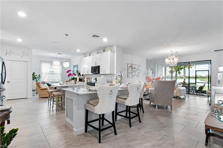 Kitchen featuring a chandelier, a peninsula, a breakfast bar, white cabinets, and recessed lighting