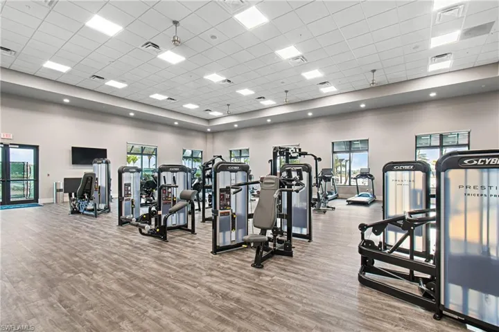 Workout area featuring a drop ceiling, wood finished floors, and a high ceiling