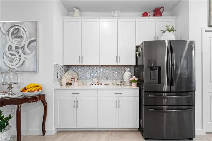 Kitchen featuring stainless steel fridge with ice dispenser, tasteful backsplash, light countertops, white cabinetry, and light wood-style flooring