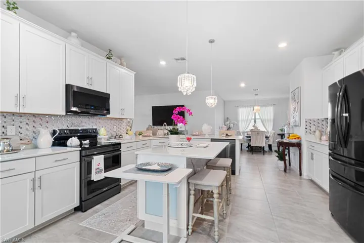 Kitchen with decorative backsplash, black appliances, light countertops, and recessed lighting