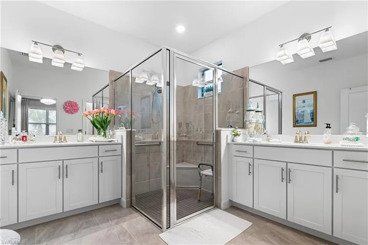 Full bath with two vanities, a shower stall, and healthy amount of natural light