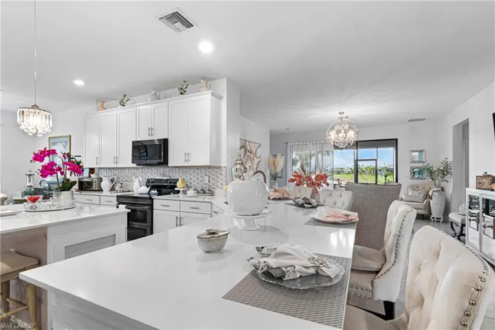 Kitchen with a chandelier, electric stove, light countertops, a breakfast bar area, and recessed lighting