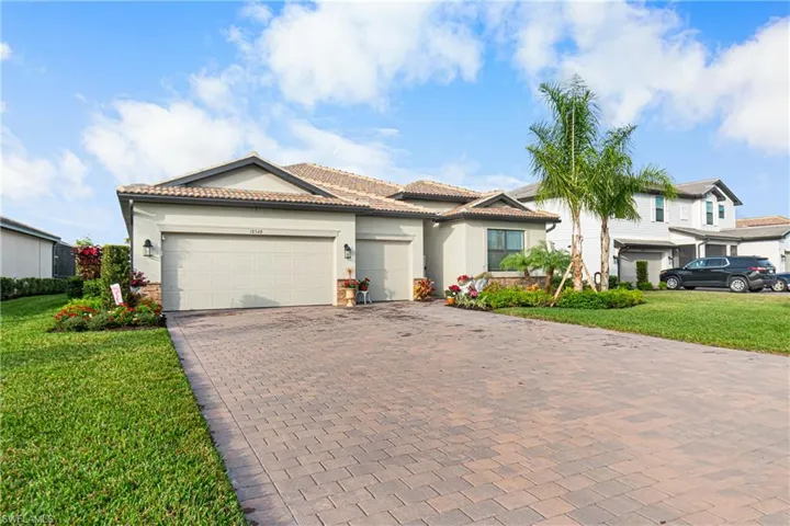 View of front of property featuring a front yard, a garage, decorative driveway, and stucco siding