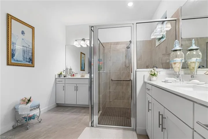Full bathroom featuring two vanities and a stall shower