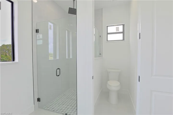 Bathroom featuring toilet, a stall shower, baseboards, and tile patterned floors