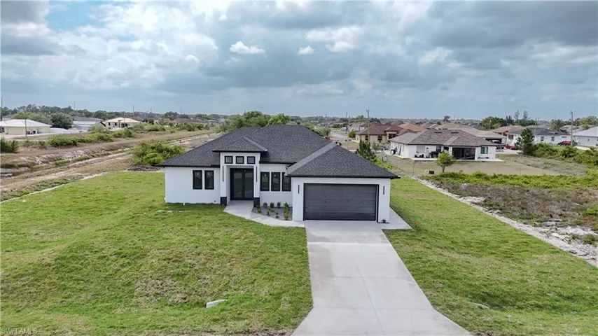 View of front of house with driveway, an attached garage, a front lawn, and a residential view