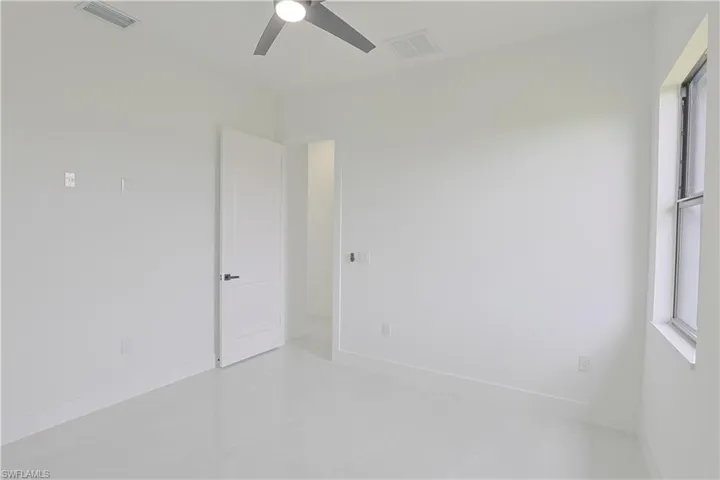 Empty room featuring baseboards, finished concrete flooring, visible vents, and a ceiling fan