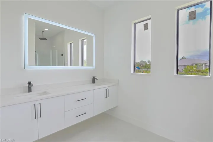 Bathroom with double vanity, a sink, baseboards, and walk in shower