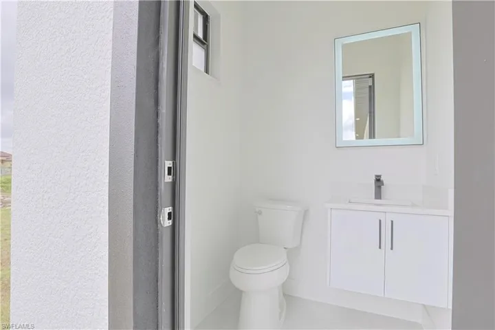 Half bathroom with toilet, vanity, and baseboards