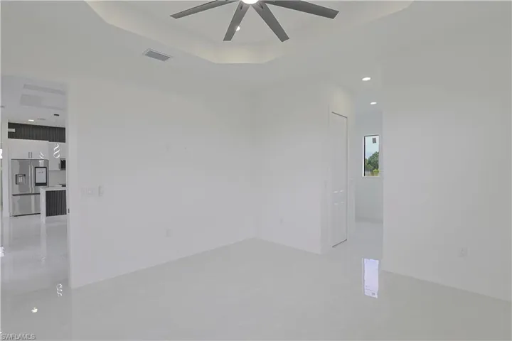 Spare room with a ceiling fan, baseboards, a raised ceiling, and visible vents