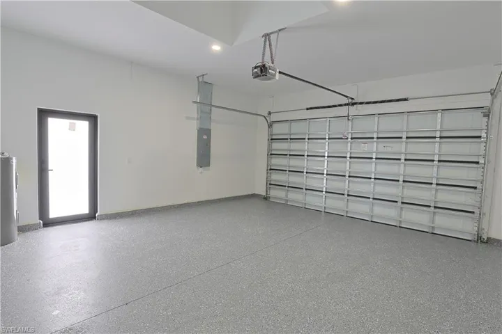 Garage with electric panel, a garage door opener, and water heater