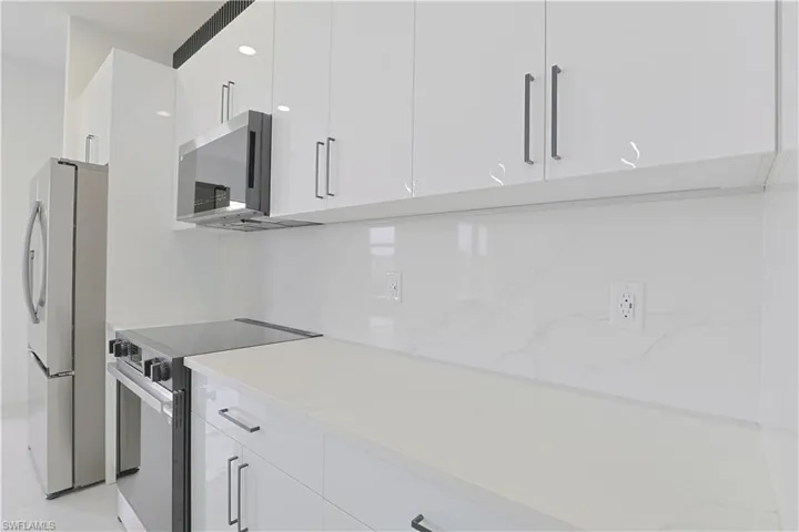 Kitchen with white cabinetry, light stone countertops, appliances with stainless steel finishes, modern cabinets, and decorative backsplash